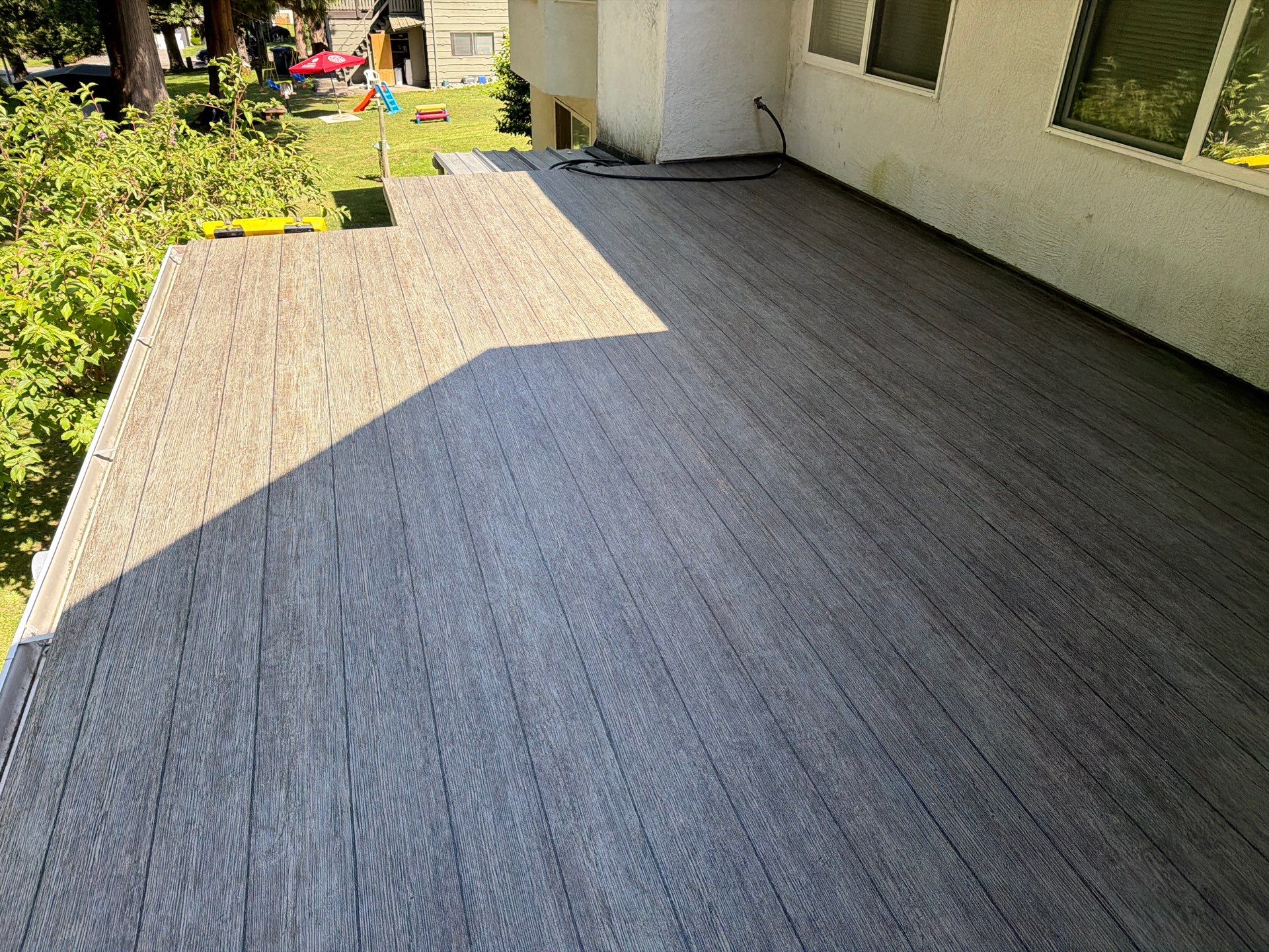 Valordek Walnut Plank vinyl decking membrane on a large, sunlit deck