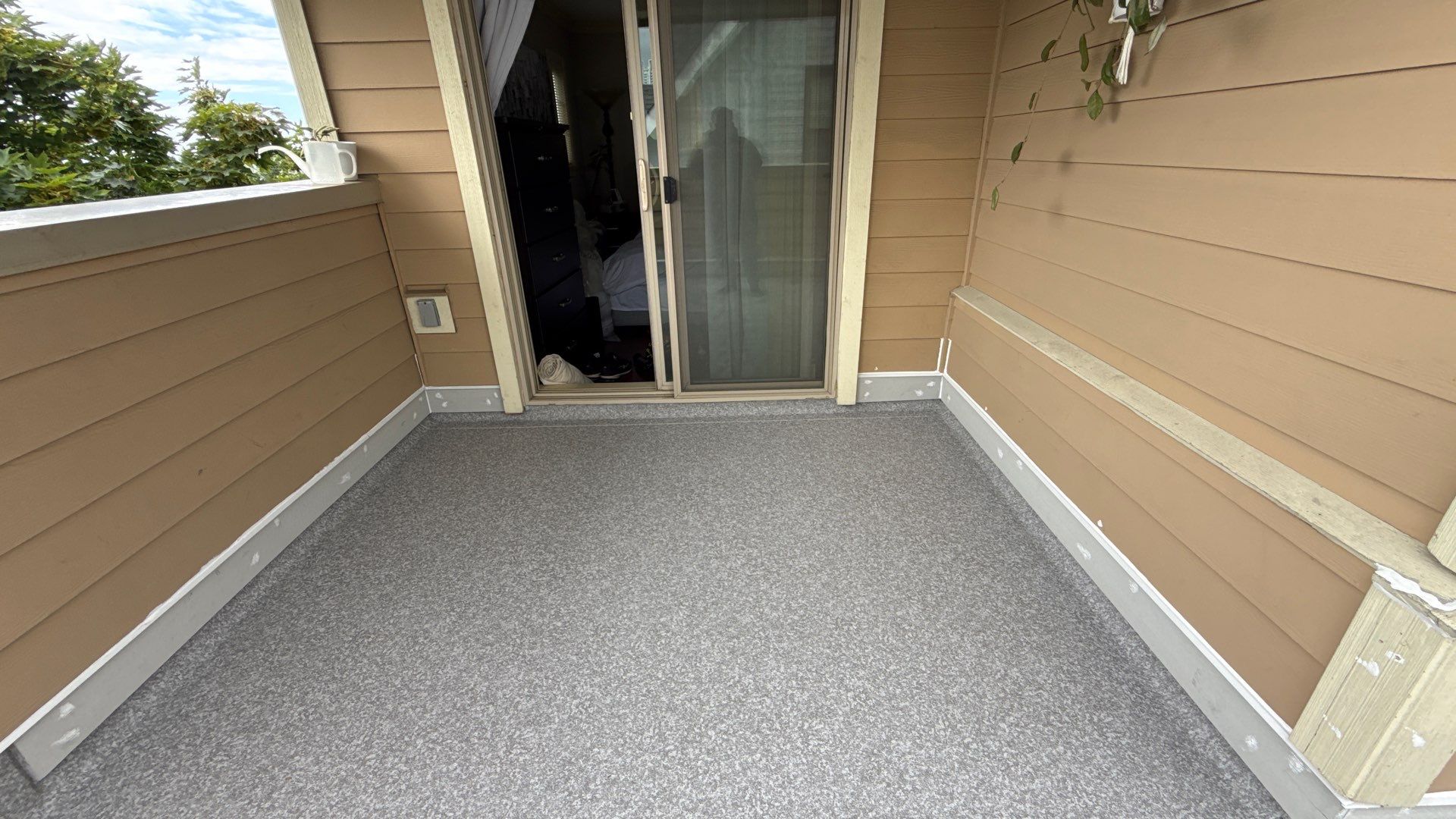 Valordek Flint Taupe vinyl decking membrane on an enclosed balcony outside a sliding door