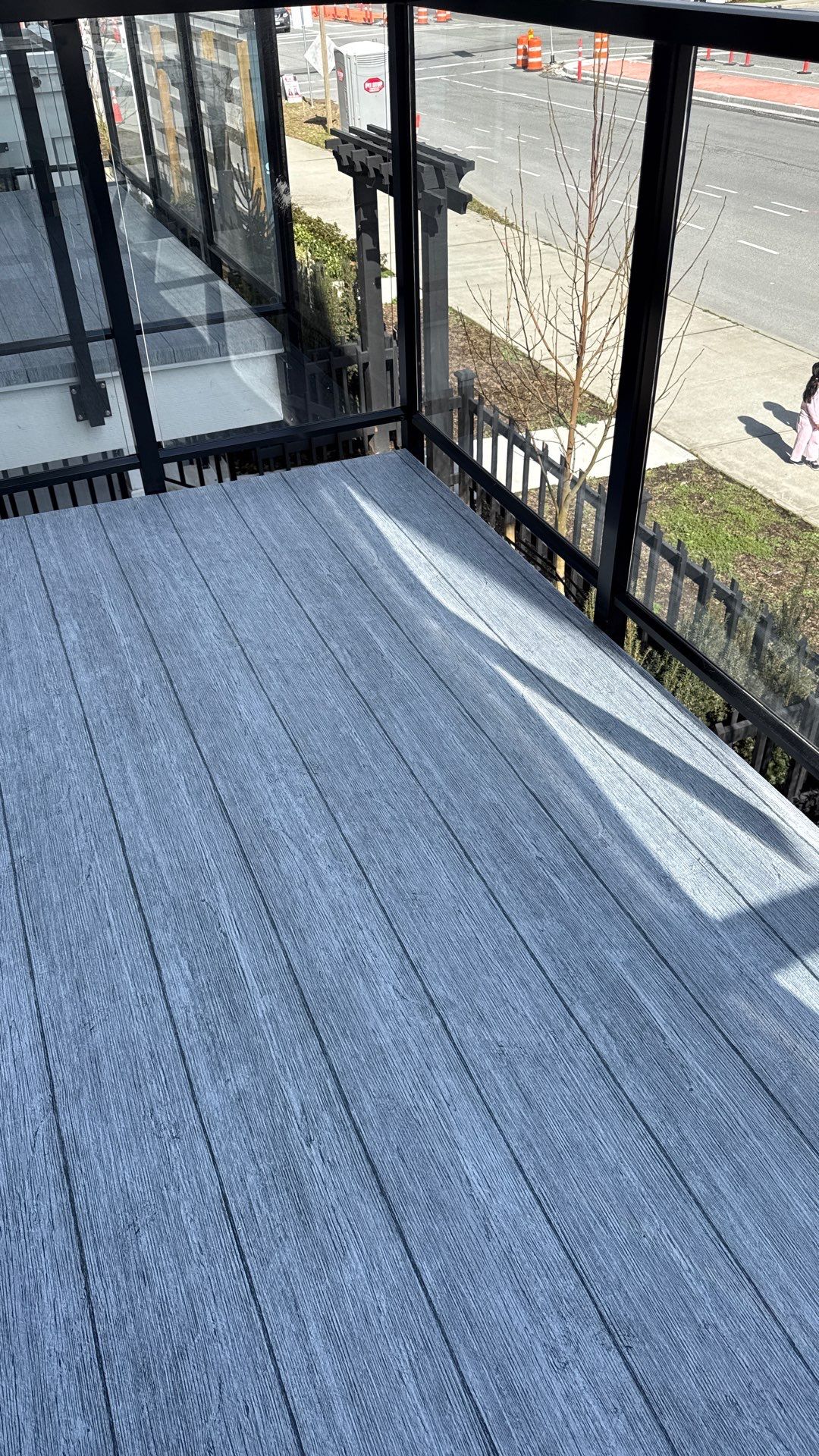 Valordek Ash Plank vinyl decking lying flat on a balcony in full afternoon sun