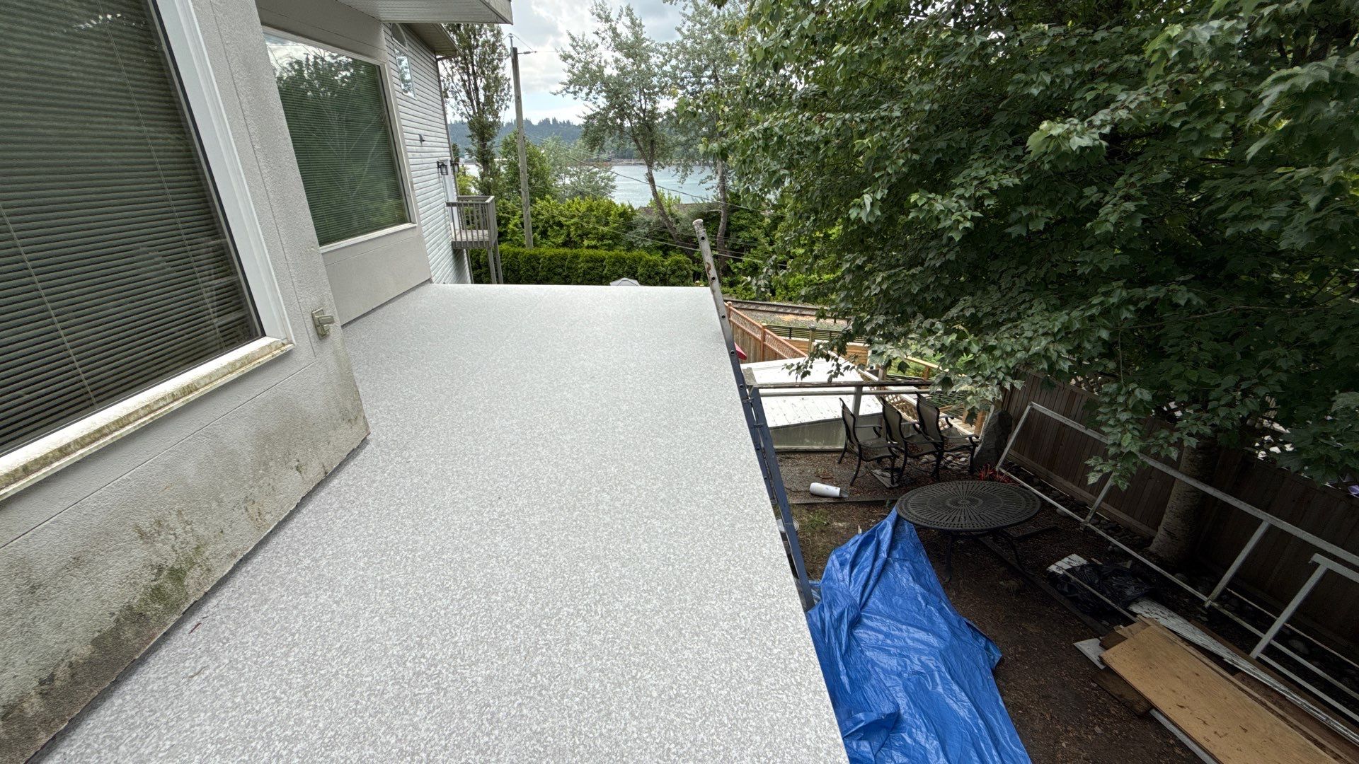 Valordek Flint Taupe vinyl decking on an upper-floor balcony, with an outdoor seating area on the level below