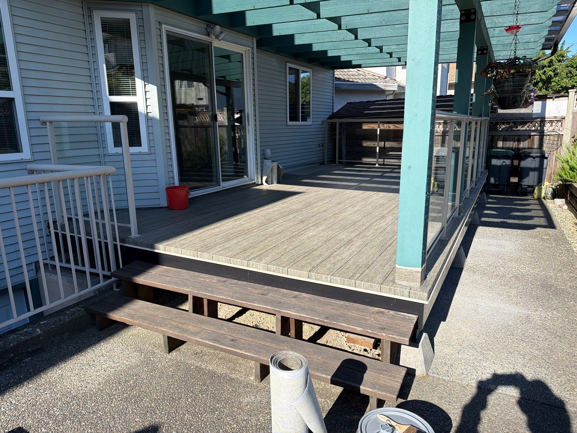 Valordek Walnut Plank vinyl decking on a covered deck with a pergola and glass railing