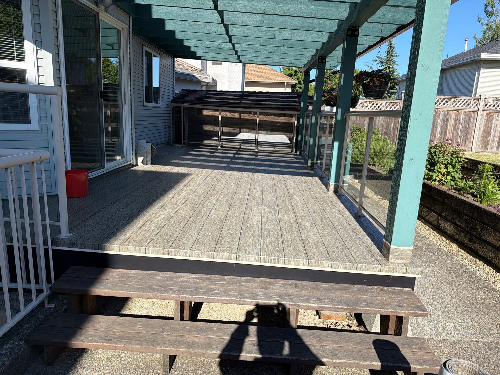 Valordek Walnut Plank vinyl decking membrane on a covered residential deck with glass railing